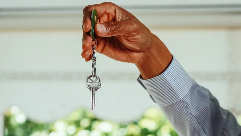 Main tenant des clés avec un porte-clés vert, arrière-plan flou