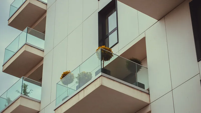 Balcons d'appartement modernes avec garde-corps en verre et plantes en pots.
