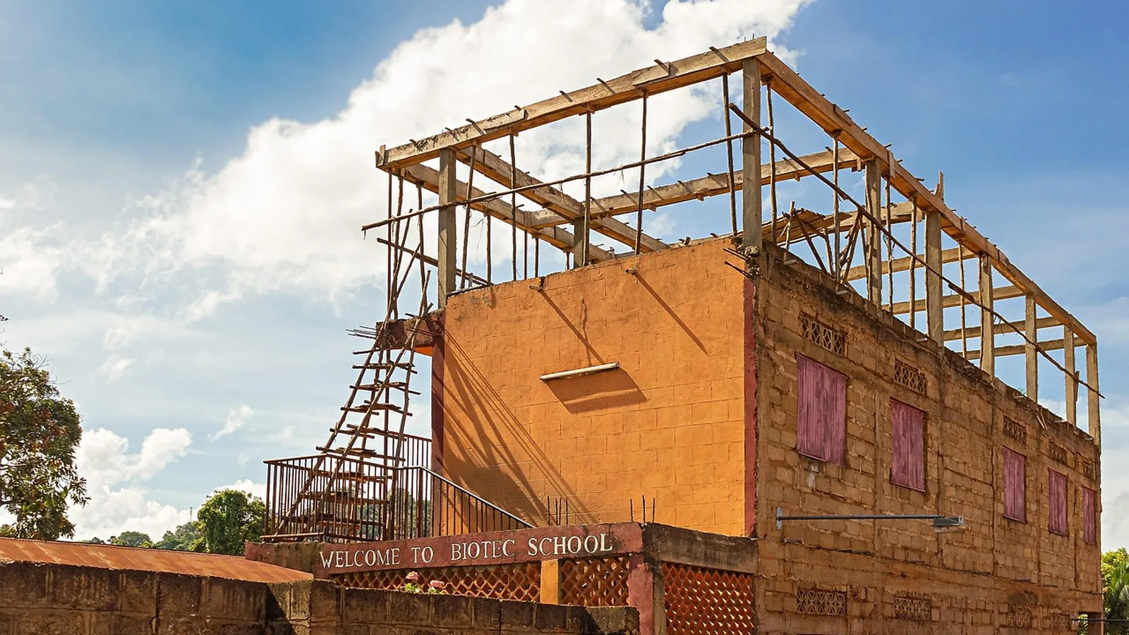 Bâtiment en briques de latérite avec structure de toit en bois en cours de construction, Afrique de l'Ouest