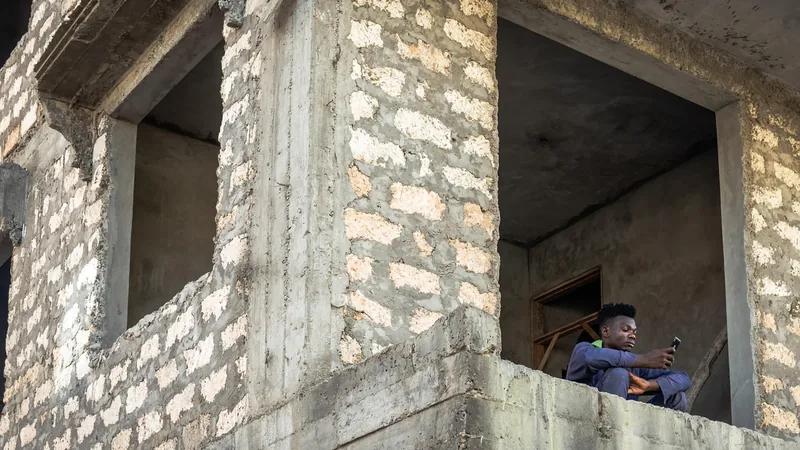 Un homme assis dans une fenêtre d'un bâtiment en construction en béton brut.