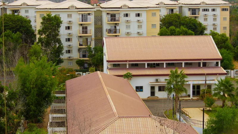 Vue aérienne d'immeubles résidentiels et de maisons avec toits en tuiles entourés de végétation tropicale