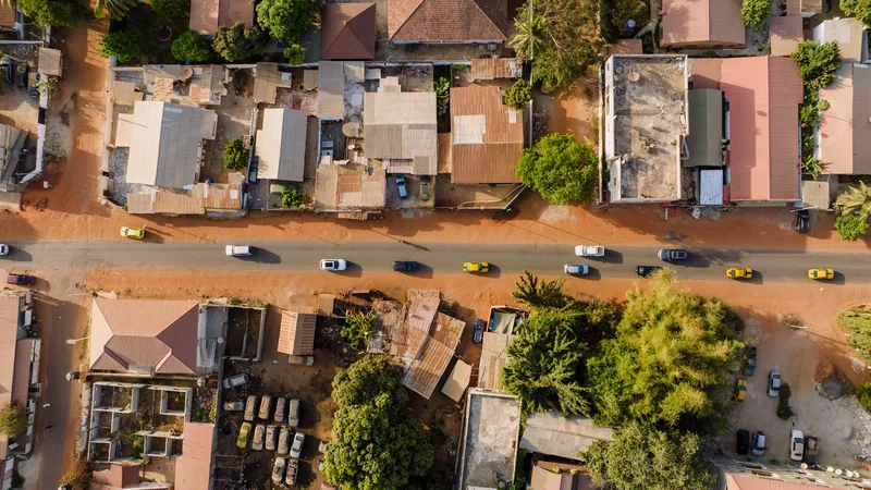 Vue aérienne d'un quartier résidentiel avec des rues en terre rouge et des maisons aux toits de tôle