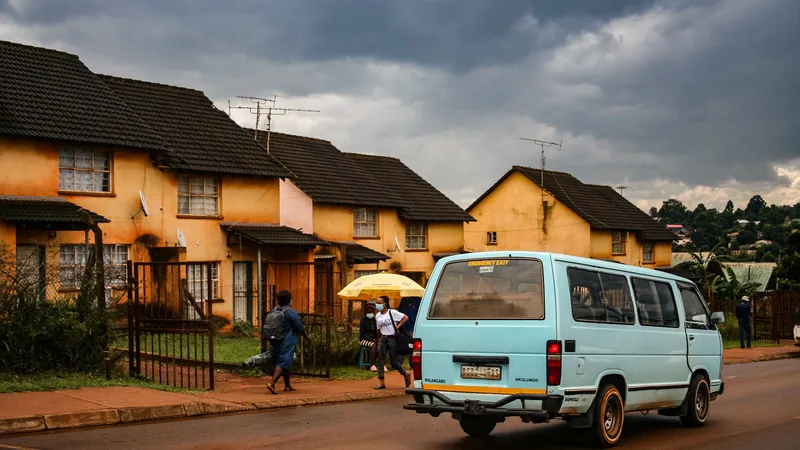 Rue résidentielle africaine avec des maisons en rangée, un minibus bleu et des passants