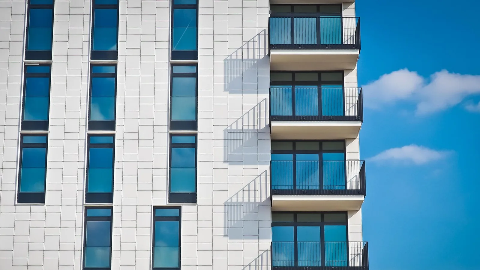 Modern apartment building facade with balconies and blue windows