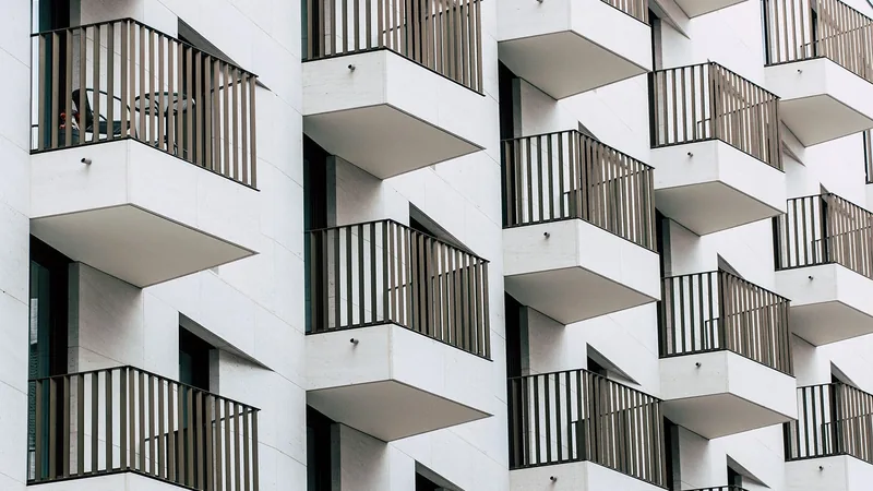 Façade d'immeuble moderne avec balcons géométriques blancs et garde-corps noirs