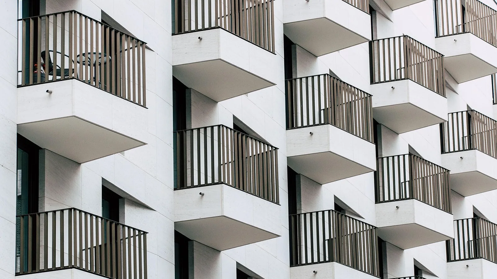 Façade d'immeuble moderne avec balcons géométriques blancs et garde-corps noirs