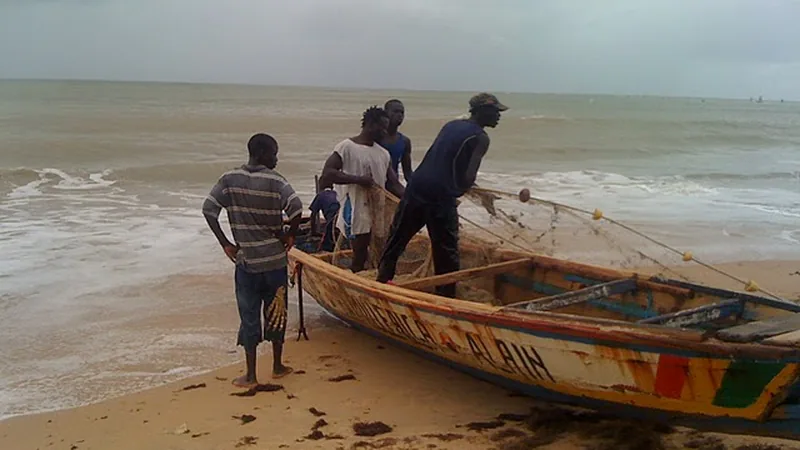 Pêcheurs poussant une pirogue en bois sur une plage de sable