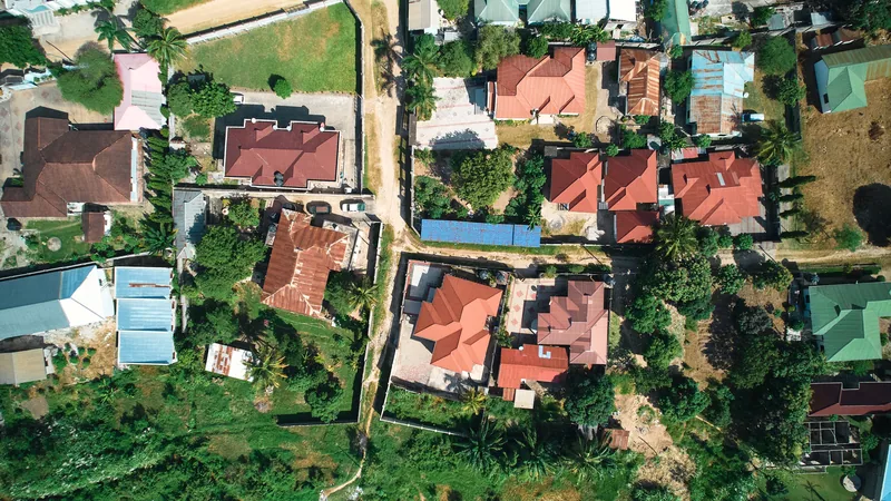 Vue aérienne d'un quartier résidentiel avec maisons aux toits rouges et végétation tropicale