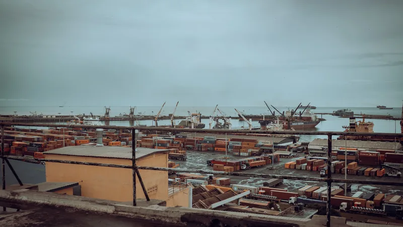 Vue sur un port industriel avec conteneurs, grues et navires sous un ciel couvert