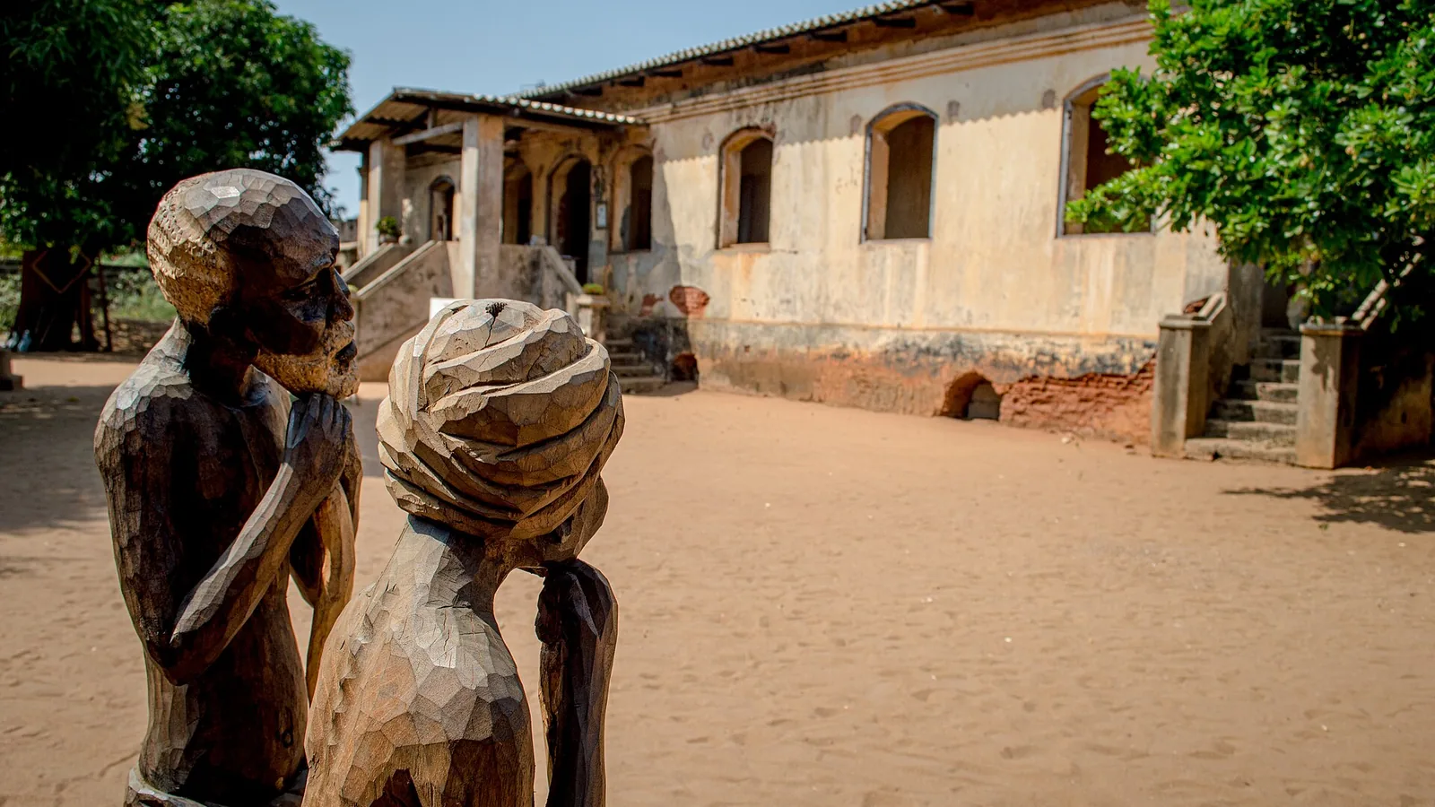Colonial building with veranda and wooden sculptures on red ground, West African architecture