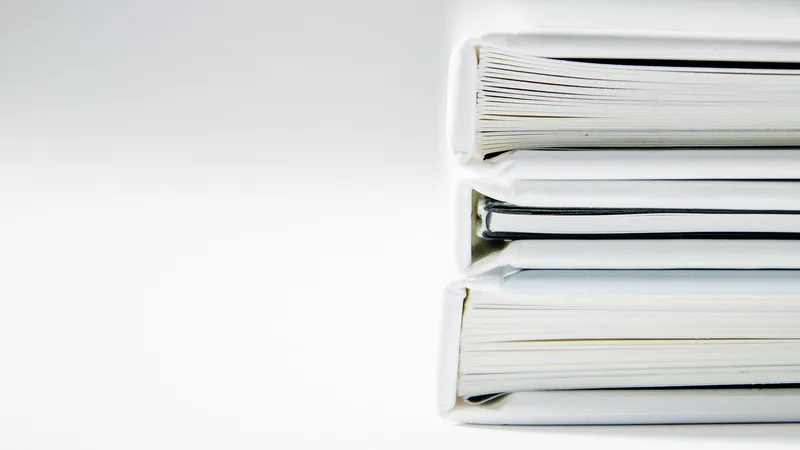 Stack of white binders full of documents on a light background