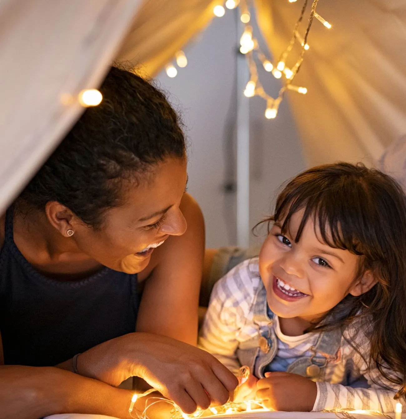 Allara, Eglinton mother and daughter smiling while laying in teepee.