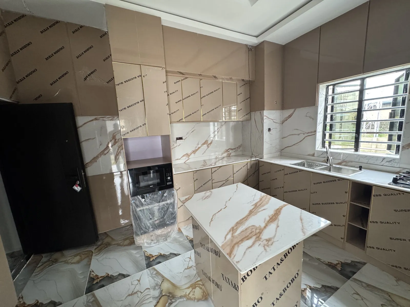 Wide angle view of a contemporary kitchen showcasing high-end protective finishes on the cabinetry and a large stainless steel double sink