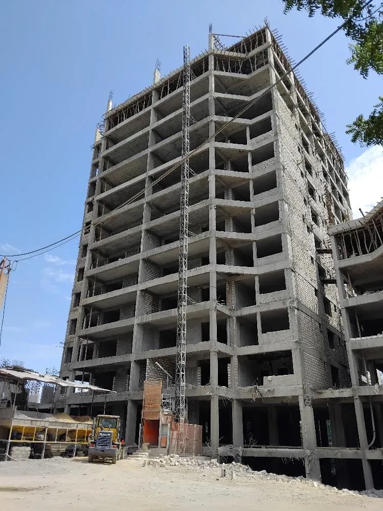 Multi-storey concrete frame of Aquavista Residences, Nyali, under construction, with a tall lattice mast against blue sky