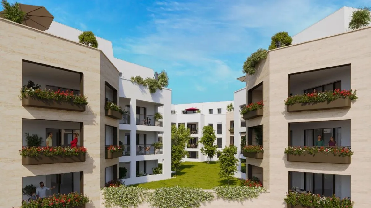 Vue extérieure de la résidence Cap A Vita, montrant des bâtiments modernes entourés de verdure, avec des allées arborées et un parc central.
