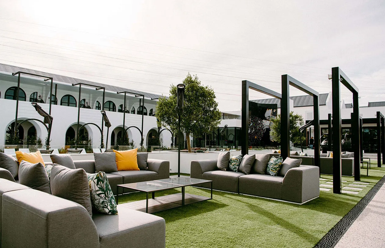 Rooftop lounge area featuring contemporary outdoor sofas, lush greenery, and shaded pergolas for rel.